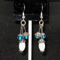 Pair of earrings with blue and white beads on a black background