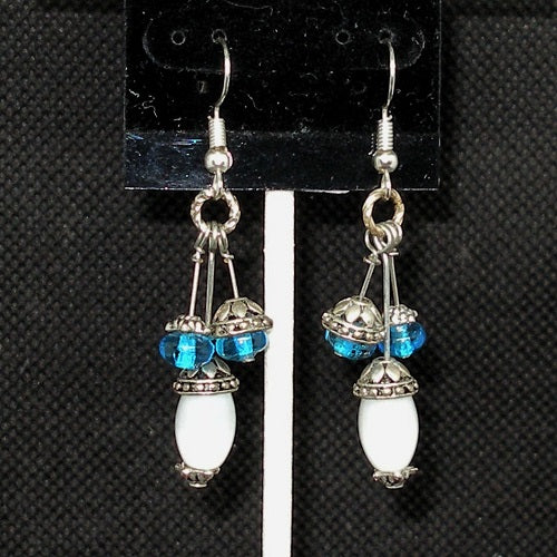 Pair of earrings with blue and white beads on a black background