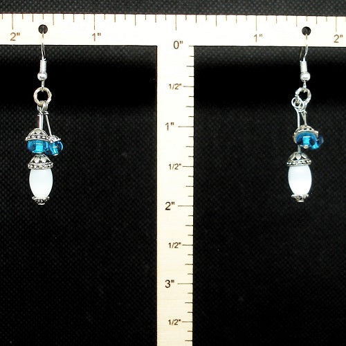 Pair of earrings with blue and white stones on a black background with a ruler for scale.