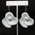 White floral earrings on a black background