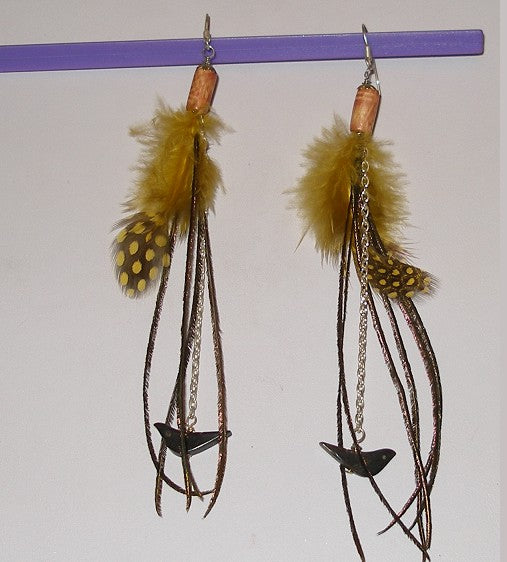 Pair of earrings with yellow feather-like elements and chain details on a white background