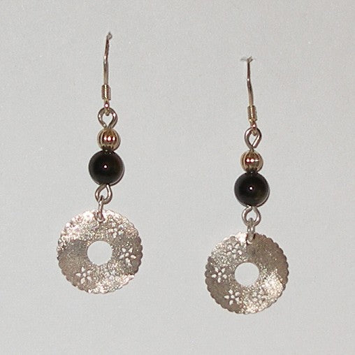 Pair of silver earrings with black beads on a light gray background