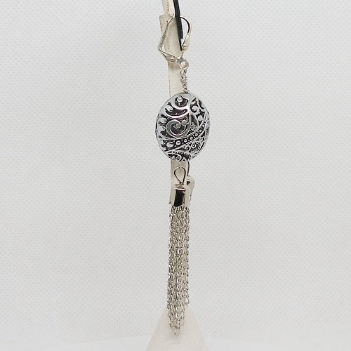 Silver dangle earring with decorative design on a light gray background