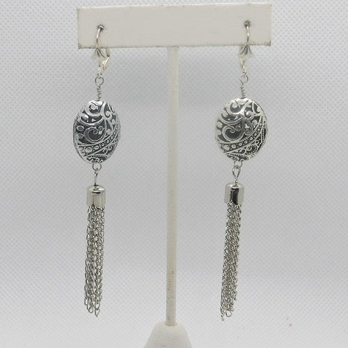 Pair of silver earrings with intricate designs on a white background
