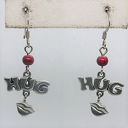 Silver 'HUG' earrings with red beads on a white card