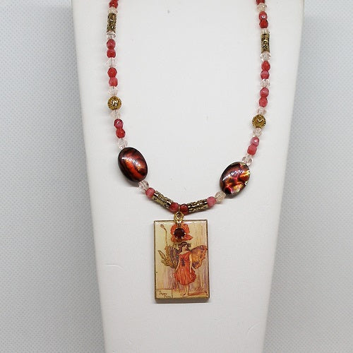 Necklace with red and gold beads and a rectangular pendant on a white stand.