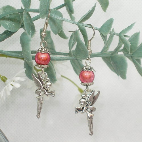 Pair of fairy-themed earrings with pink beads on a green leaf background