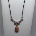 Necklace with a pink stone pendant on a white stand