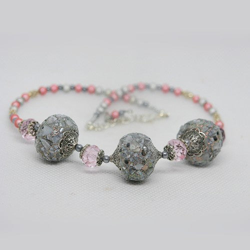 Necklace with gray and pink beads on a light gray background