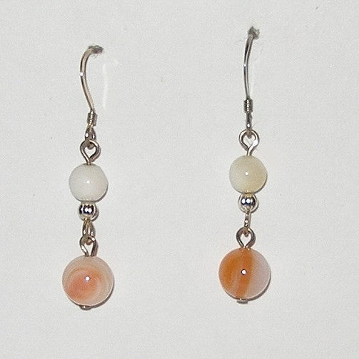 Pair of earrings with white and peach-colored beads on a white background