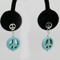 Peace sign earrings with turquoise peace symbol on a black velvet stand against a white background