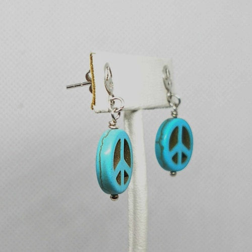 Turquoise peace sign earrings on a gray background