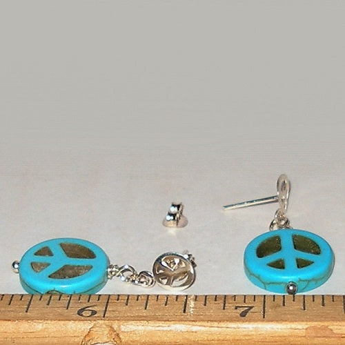 Turquoise peace sign earrings with silver accents on a white background, shown next to a ruler for size reference.