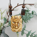 Carved bone dragon pendant on a necklace with beads, against a white background with greenery.