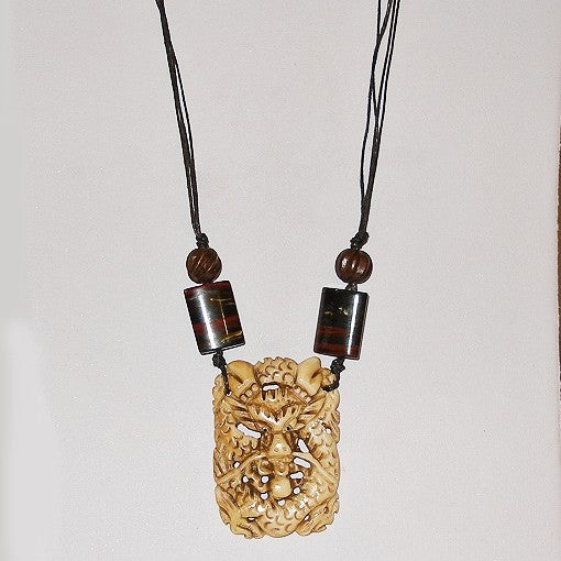 Carved pendant necklace with decorative elements on a plain background