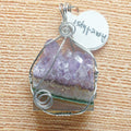Amethyst crystal pendant in a silver wire wrap on a textured surface