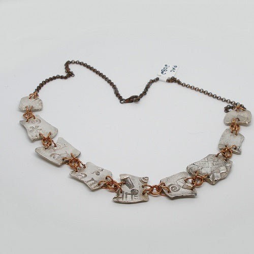 Silver necklace with unique links on a white background