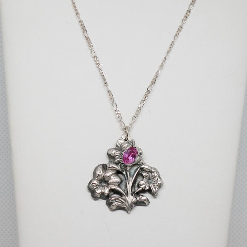 Silver necklace with floral pendant and pink gemstone on a white background