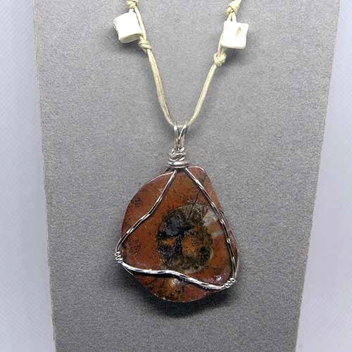 Necklace with a fossil ammonite pendant on a gray background