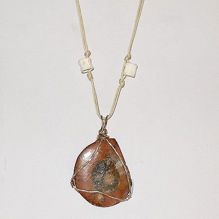 Necklace with a large, fossil pendant on a plain background