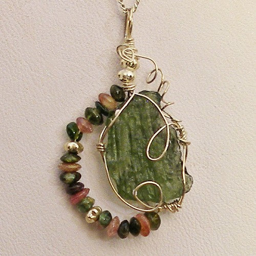 Jewelry pendant with green stone and multicolored beads on a light background
