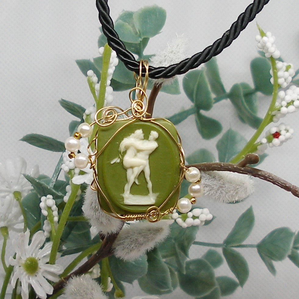 Necklace with a green cameo pendant featuring a classical design, surrounded by green leaves and white flowers.
