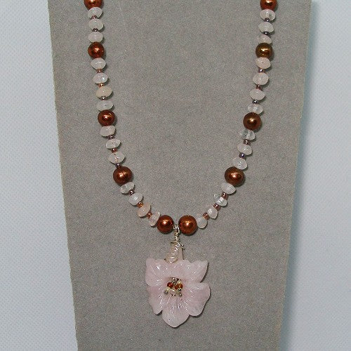 Necklace with beads and a pink flower pendant on a gray background