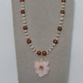 Necklace with beads and a pink flower pendant on a gray background
