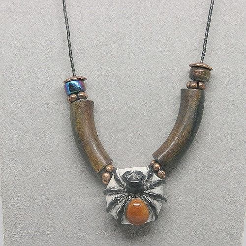 Necklace with brown wood beads and a clay spider pendant on a gray background
