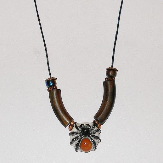 Necklace with brown cylindrical beads and a spider pendant on a white background