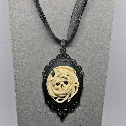 Skull and dragon pendant necklace on a gray card