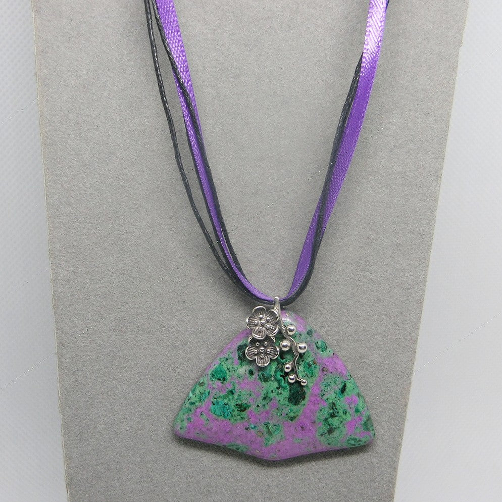 Necklace with a green and purple pendant on a gray card