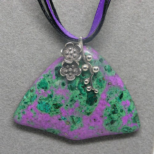 Necklace with a green and purple stone pendant and silver bail on a gray background