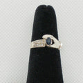 Silver ring with a blue gemstone on a black velvet stand against a light gray background