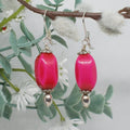 Pink beaded earrings with silver hooks on a branch with white flowers