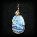 Blue marbled pendant with silver wire wrapping on a black background