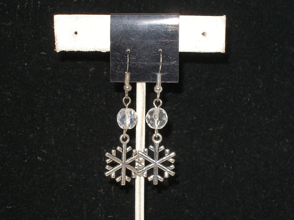 Silver snowflake earrings with clear crystals on a black background