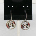 Earrings with circular designs of a famous actress on a black card.