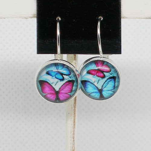 Butterfly earrings on a black card with a white background
