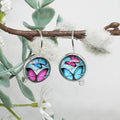 Butterfly-themed earrings hanging on a branch with a natural background