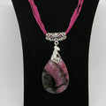 Necklace with a pink and black stone pendant on a black stand.
