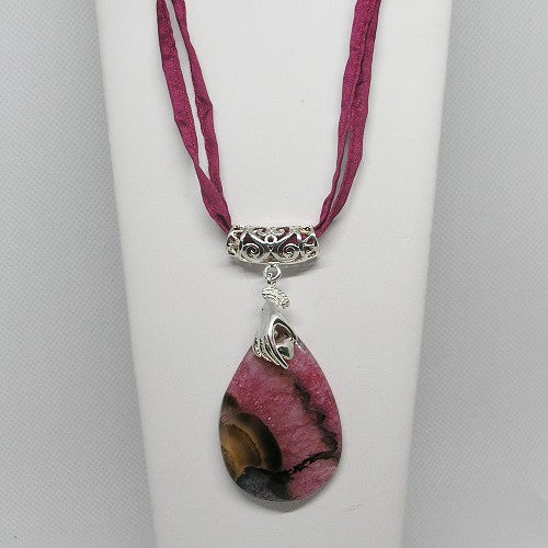 Necklace with a pink and brown teardrop pendant on a white stand.