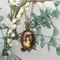 Necklace with a pendant featuring a portrait against a floral background