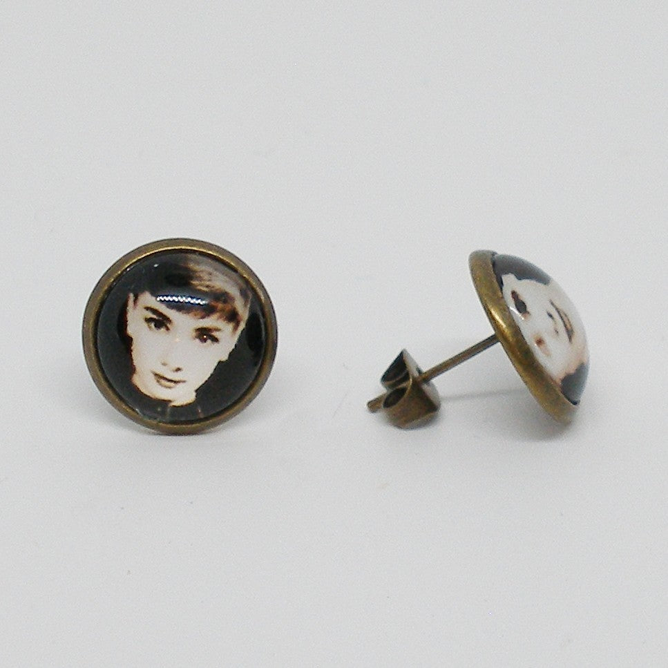 Pair of earrings with portrait designs on a light gray background