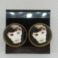 Pair of earrings with a portrait design on a gray background