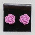 Pair of purple rose-shaped earrings on a black card with a gray background