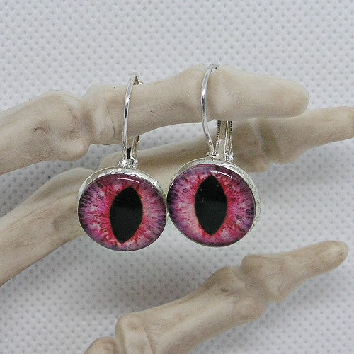 Earrings with purple and pink eye design on a mannequin hand against a white background