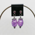 Purple beaded earrings with purple crystals on a black card against a white background
