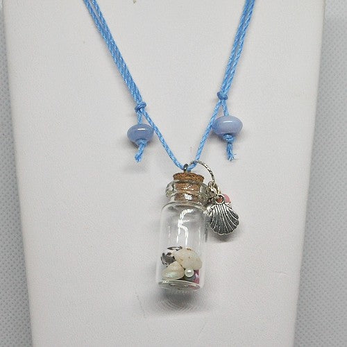 Necklace with a small glass jar pendant containing shells and stones on a white background