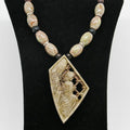 Necklace with beads and a decorative pendant on a black stand.